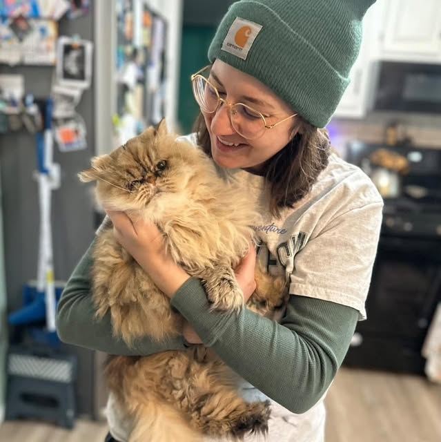 A sitter hugging a fluffy Persian cat during a drop-in visit